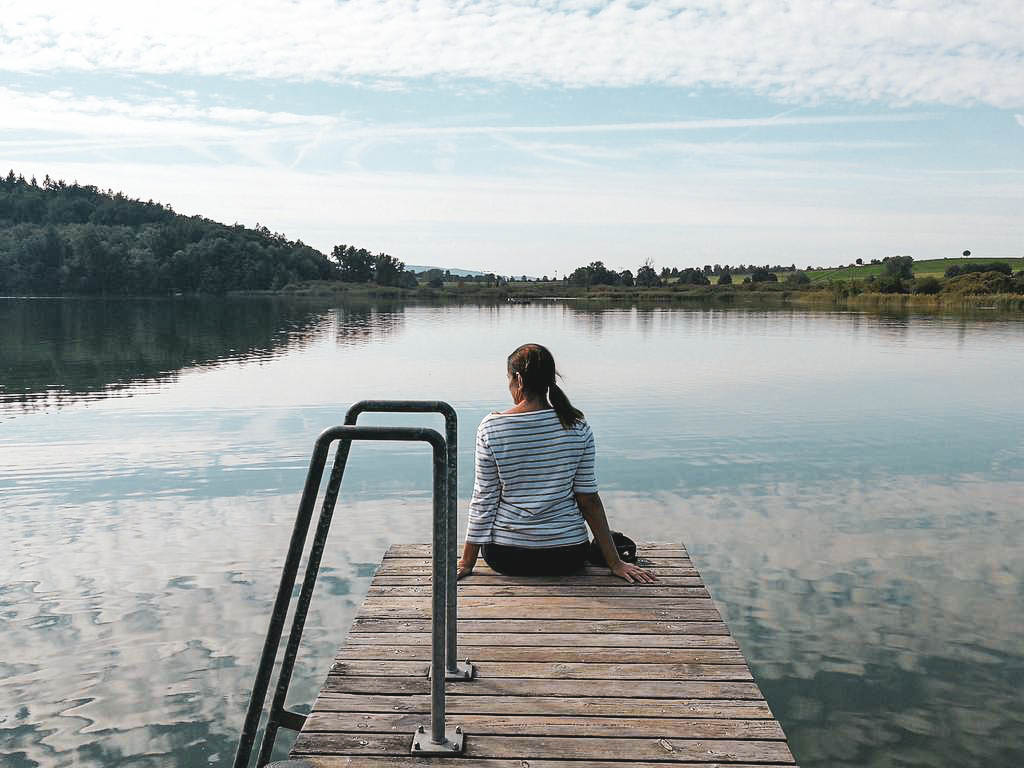 Frau sitzt an einem See